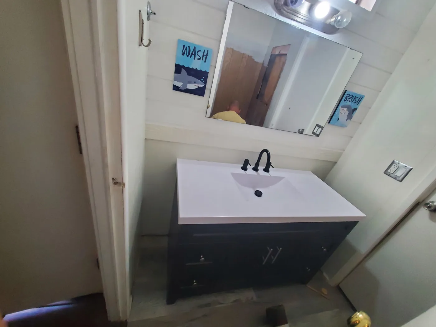 After: Finished bathroom with a new dark vanity, stone-look top, and fixtures